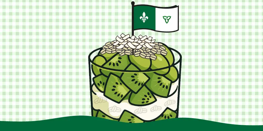 Une verrine contenant, de façon étagée, du yogourt blanc, des flocons d’avoine, des morceaux de kiwi et des raisins verts. Sur le dessus, il y a des flocons de noix de coco et un petit drapeau franco-ontarien planté au sommet.